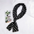 Detail eines schwarz-weißen schmalen Polka-Dot-Seidenschals auf weißem strukturiertem Hintergrund - Schwarz