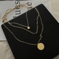 Collier superposé doré à trois couches avec pendentifs ronds sur un support noir - Doré