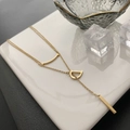 Golden D pendant necklace with curved bar and rectangle drop on white ceramic background - Gold
