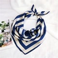 Dettaglio di un foulard in seta a righe blu e crema annodato su uno sfondo bianco - 70cm / Lettere a Labirinto Blu
