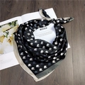Close-up of a silk square scarf with equestrian horse head print on a wooden desk - 21 Little Horse Black