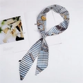 Dettaglio di un foulard twilly in seta con motivo pied-de-poule su una rivista - 2H Blu