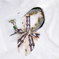 Detail of silk twilly scarf with horse and harness print tied in a bow on a magazine - 37 Apricot Horse Pattern