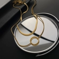 Goldene flache Schlangenkette mit minimalistischem Kreisanhänger auf Spiegeloberfläche - Gold