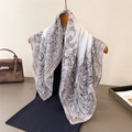 Elegant floral print silk scarf with black scroll patterns hanging on a wooden hanger - White