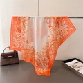 Elegant orange silk-like scarf with baroque floral prints on a display rack - Orange