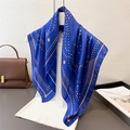 Fashionable geometric silk scarf in royal blue and orange pattern draped over white vest - Blue