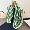 Eleganter grün-weißer Seidenschal mit Chevron-Muster an einem Kleiderbügel mit Modetaschen - Grün