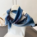Close-up of a blue geometric silk scarf styled on a white vest with elegant patterns - Blue
