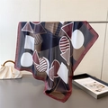 Detailed drape of geometric faux silk scarf featuring burgundy and navy artistic patterns - Brown