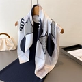 Elegant black and white geometric silk scarf draped on hanger with minimalist decor - White