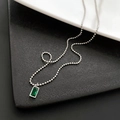 Elegante Halskette mit smaragdgrünem rechteckigem Anhänger und silberner Kugelkette auf Schwarz - Silber