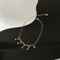 Golden crown-style anklet with V-shaped links and hanging beads on a modern tray - Gold (06-K3)