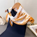 Detail showing an elegant white and orange floral faux silk scarf tied on a blue knit top - Orange (FG131-1) / 70cmx70cm