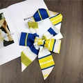 Blue and yellow striped skinny silk scarf tied in a bow on a white book and wooden table - 6 Blue and Yellow Stripe