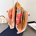 Elegant bright orange silk square scarf with red floral prints on a wooden hanger - Orange