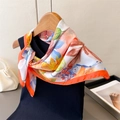 Dettaglio di un foulard in seta floreale arancione su gruccia con accessori alla moda - FG154-1 Arancione