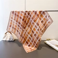 Detail of silk square scarf with vintage orange plaid pattern draped on a metal rack - 66-70cm / Brown