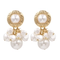 Vintage gold textured disc earrings with elegant white pearl clusters on white background - Gold