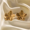 Close-up of 18K gold-plated flower stud earrings with detailed petal textures on satin - Gold Earrings