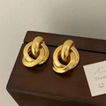 Primo piano di orecchini geometrici dorati intrecciati su una scatola di legno - Oro (D120)