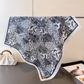 Detail of square silk scarf with black and white paisley patterns hanging on a metal rod - 70x70cm / White