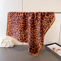 Dettaglio di un foulard in seta con stampa leopardata arancio e marrone appeso - Arancione