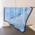 Detail of blue palm leaf print silk scarf draped over a metal rod in elegant setting - 70cm x 70cm / Blue (FG233-4)