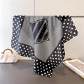 Detailed view of polka dot silk scarf draped next to a handbag on a tray - 66-70cm / Black (FG236-1)