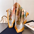 Elegant floral silk-feel square scarf with orange and beige botanical prints on a hanger - Turmeric