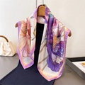 Detailed view of floral silk scarf with purple edges hanging on a wooden hanger - Purple