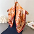 Close-up of floral silk square scarf with vibrant orange prints on a wooden hanger - 66-70cm / Dark Brown