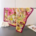 Dettaglio di un foulard di seta floreale con bordo bordeaux appeso a un supporto - 70x70cm / Borgogna