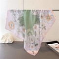 Detailed view of floral silk scarf with green and pink patterns draped over a white bag - Green