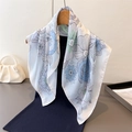 Detailed view of floral silk scarf with blue roses draped over a black garment - White