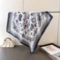 Detail of silk scarf with butterfly prints draped over a metal stand in a lifestyle setting - Black / 70cm