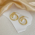 Detailed macro view of 18K gold plated geometric spiral earrings on a marble stone base - Gold (E101)