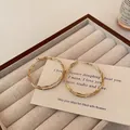 Detail of elegant gold double-hoop earrings displayed on a beige velvet jewelry box - 4cm / Gold