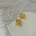 Detail of gold lava textured irregular earrings resting on a white ceramic tray - Gold Style (D203)