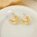 Détail de créoles en résine et métal doré en forme de C sur un plat en céramique - Blanc Crème (c202)
