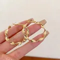 Macro-opname van gouden gedraaide gedraaide oorringen met een veilige kliksluiting - Gouden Gedraaide Stijl (F316)