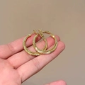 Detailaufnahme goldener zweilagiger Creolen mit strukturierter Oberfläche in der Hand - Gold 3cm