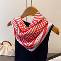 Close-up of red and white polka dot silk scarf draped over a black top on wooden hanger - 70x70cm / Red