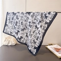 Detail of silk scarf with hand-drawn animal prints and black borders hanging on a rack - White