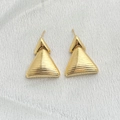 Detalle de pendientes triangulares dorados con una refinada textura de metal cepillado - Dorado
