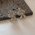 Dettaglio degli orecchini a fiore in argento lucido presentati su roccia vulcanica scura - Argento