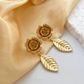 Détail de boucles d'oreilles fleur dorée avec texture de feuille sur tissu en soie - Doré