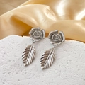 Boucles d'oreilles fleur et feuille en argent poli sur socle blanc et fond en soie dorée - Argenté