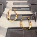 Macro view of golden Mobius hoop earrings with twisted metal texture and needle clasps - Gold (D224)