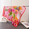 Floral silk-like square scarf in red and yellow draped on a metal display rack - Red